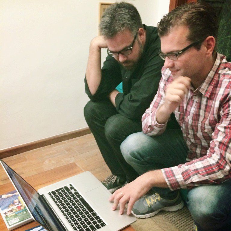 Two men sitting on the floor looking at a laptop