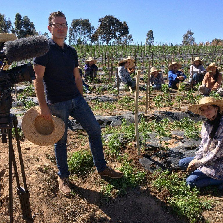A man standing in a field holding a hat