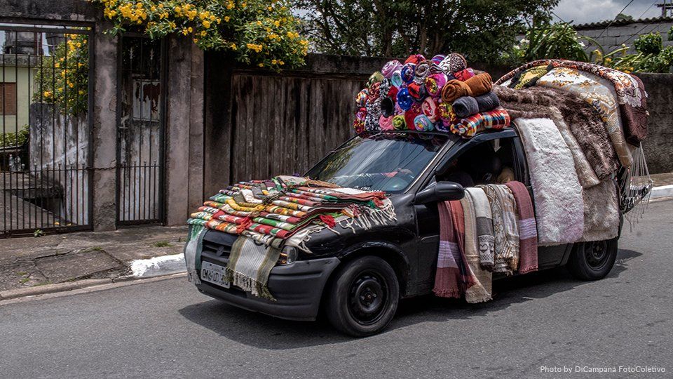 A car filled and covered by rugs drives by a street
