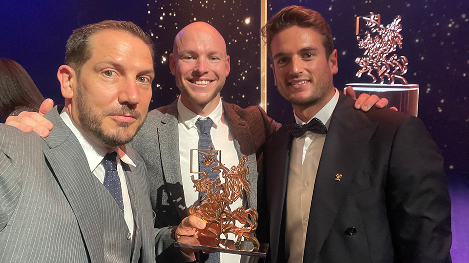 Nick Story holds the Sportel Award along with two men