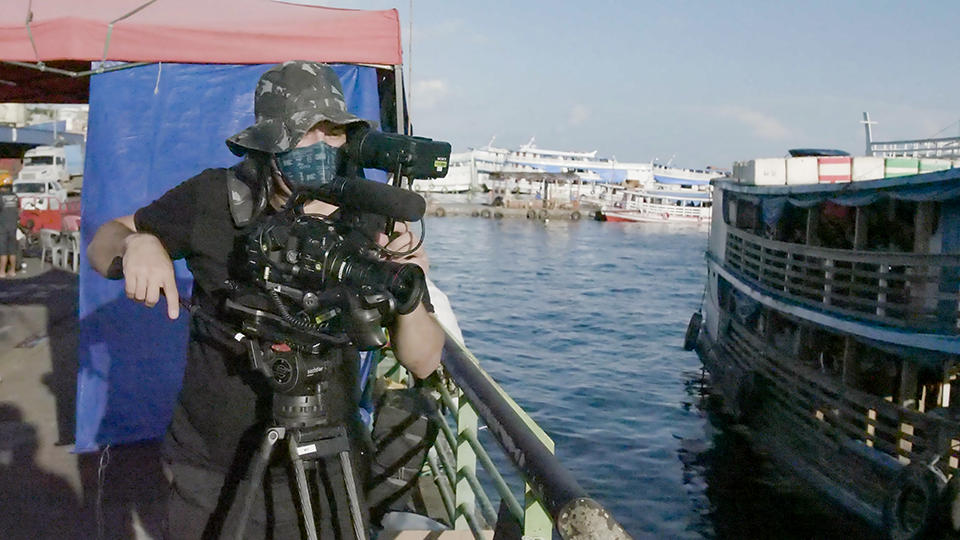 A masked camera operator films in a bay