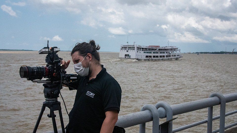 A camera operator frames the shot at a pier in Belén, Brazil