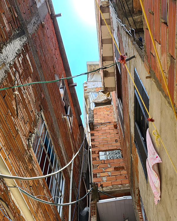 Uma passagem estreita dentro das favelas com paredes de tijolos expostos e fiação