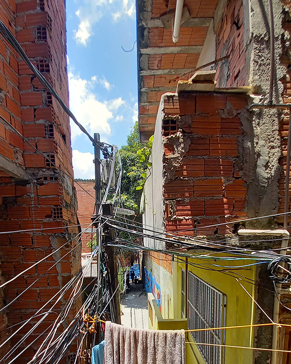 a narrow hallway within the slums with the electricity wires exposed