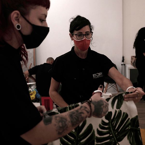 Two crew members cut fabric to make the table cloth for the video