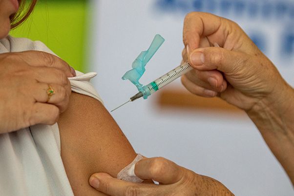 A nurse injects a vaccine into an arm of a child
