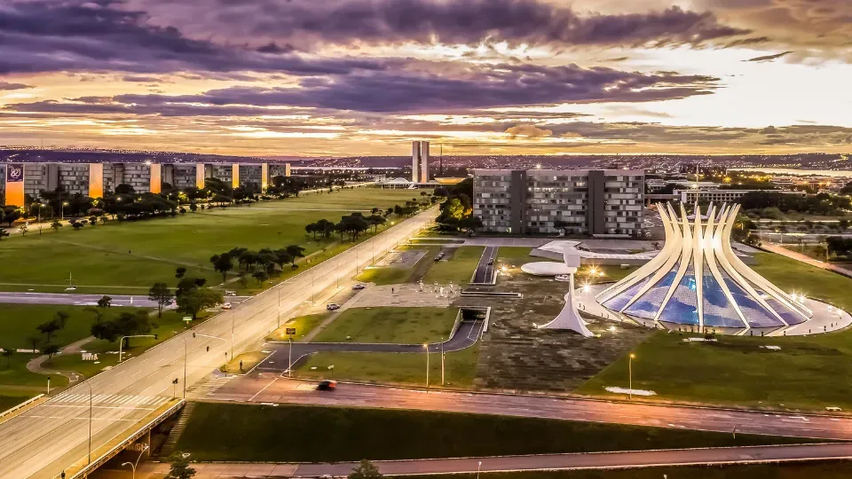 An aerial view of a city at sunset with a large dome in the middle of the city.