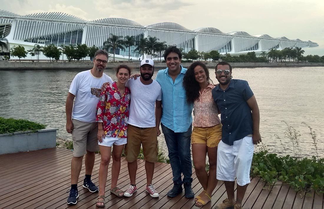 A group of people are posing for a picture in front of a body of water.