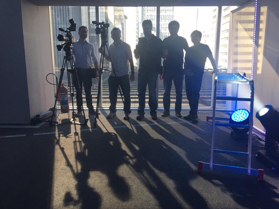 A group of people standing in front of a window with their shadows cast on the floor.