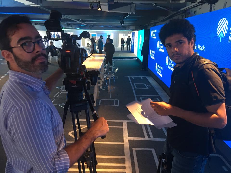 Two men are standing in front of a large screen that says cricket