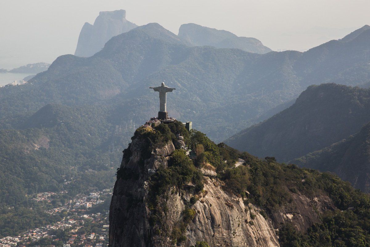 A statue of jesus is sitting on top of a mountain.
