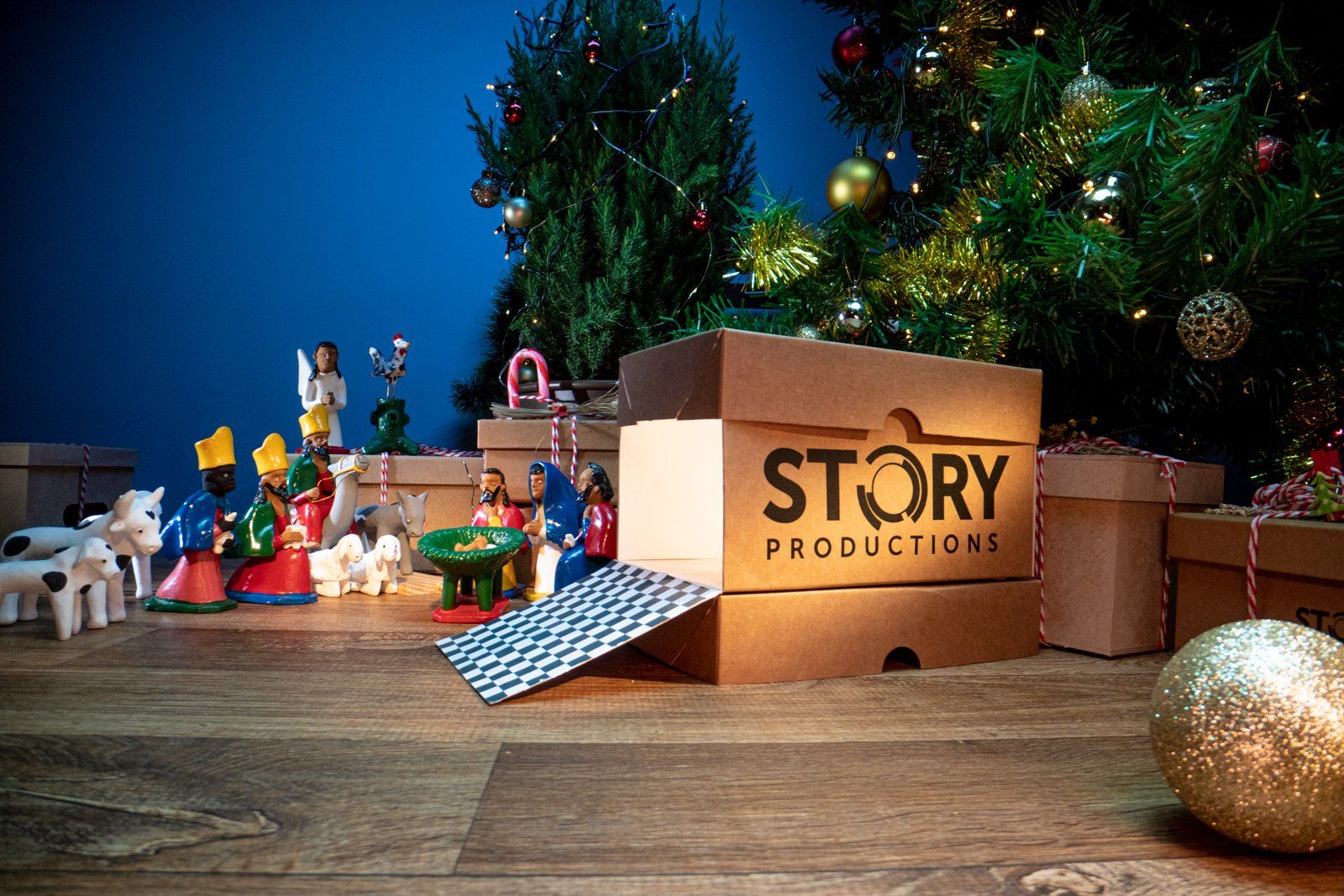 An opened box with the Story Productions logo and Christmas ornaments in the background