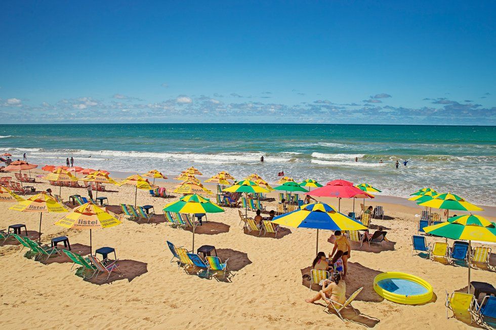 Une plage remplie de parapluies dans une journée ensoleillée avec les vagues de la mer