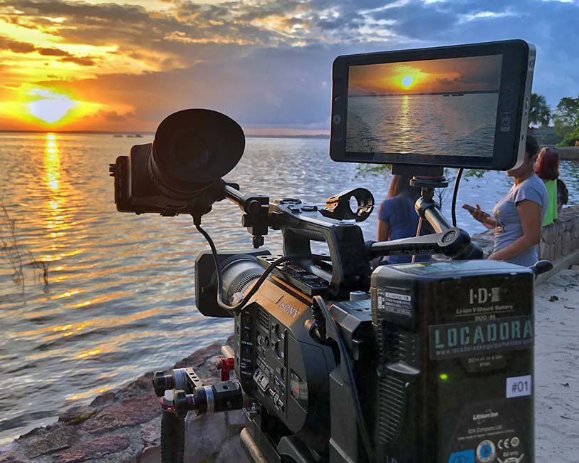 A camera is sitting on a beach with a sunset in the background.