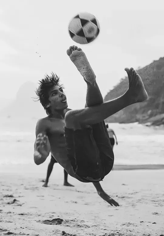 Hombre jugando al fútbol en la playa