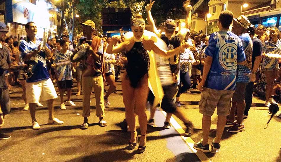 A woman in a bathing suit is dancing in front of a crowd of people.