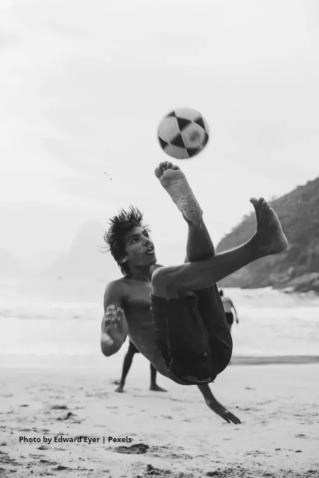 Man doing a bicycle kick on the beach