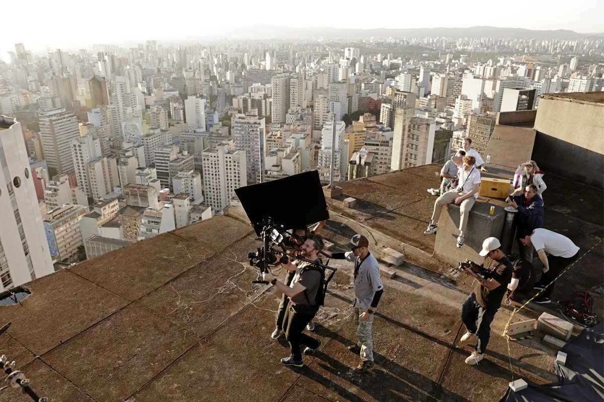 A group of people are standing on top of a roof overlooking a city.