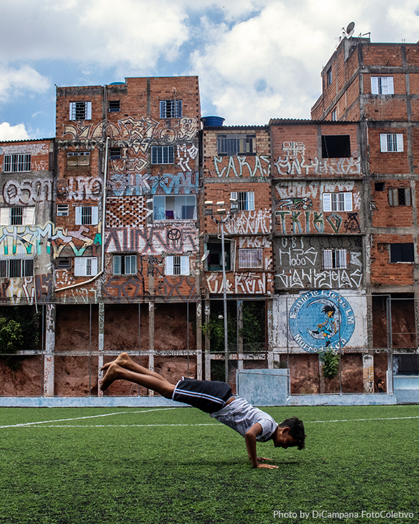 A young boy excercises in a futball field with in a community