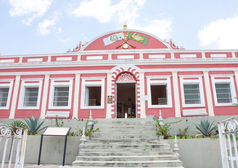 Un bâtiment rose avec des décorations détaillées blanches héberge le mémorial de Gravatá