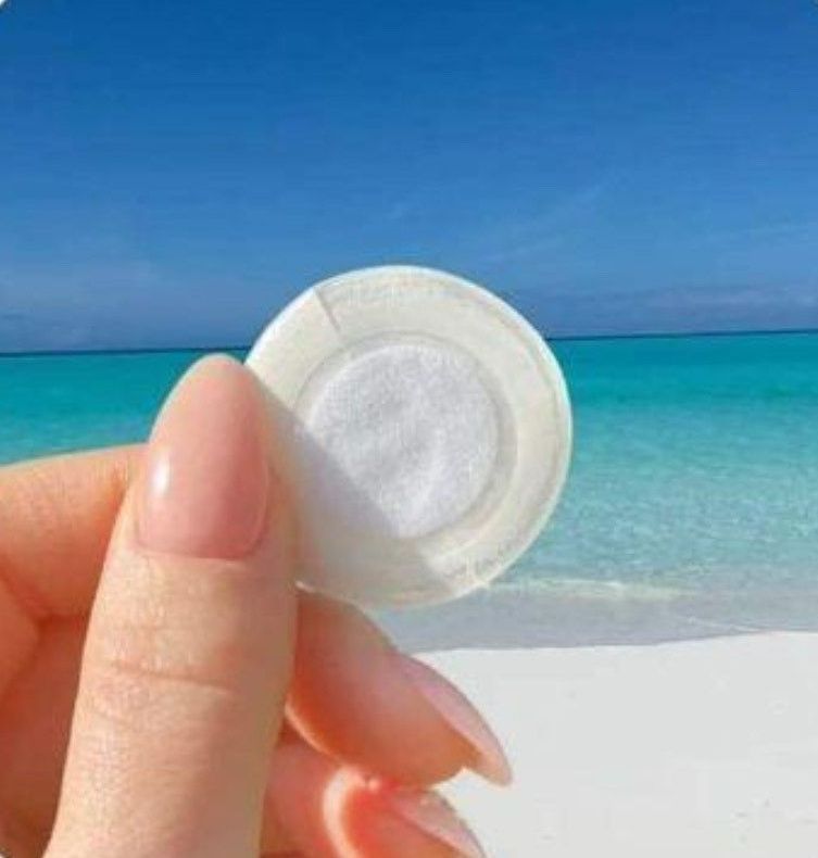 A woman with red nails is getting a patch on her neck.