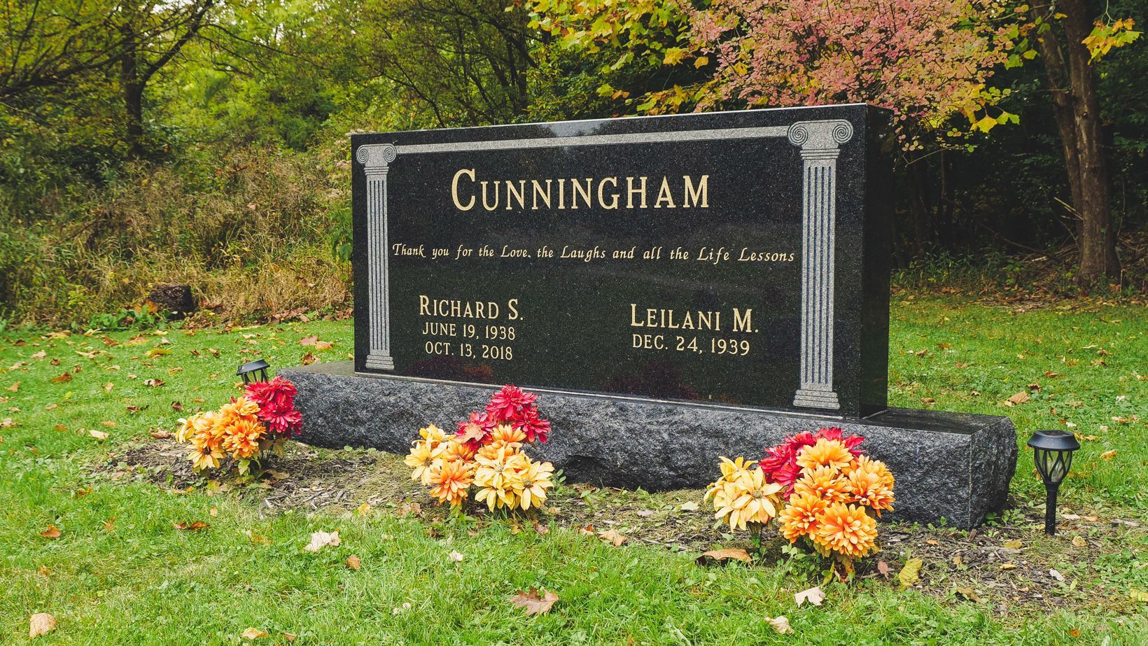 Cunningham memorial stone with flowers in a grassy cemetery garden in autumn