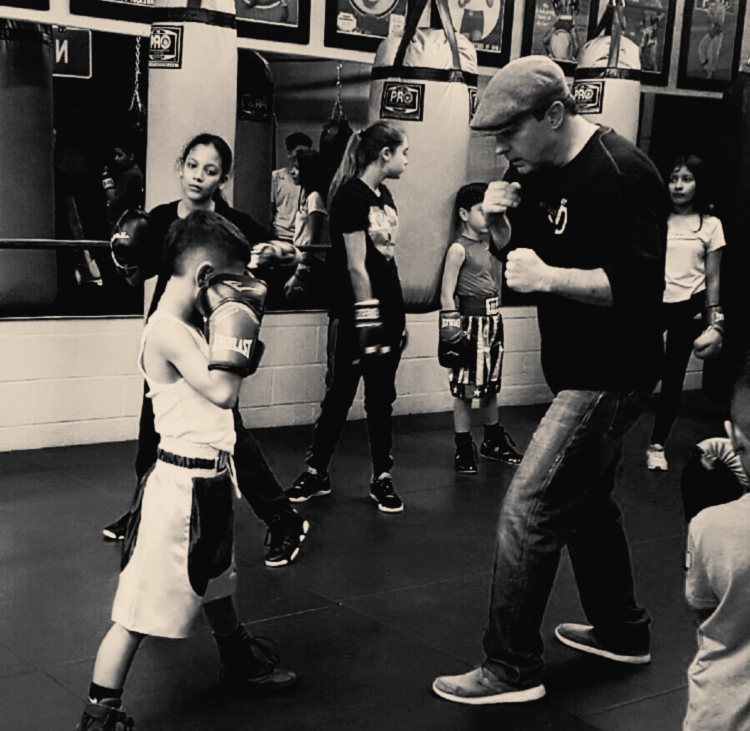 Picture of coach Desmond teaching boxing fundamentals to a young member of the boxing club.