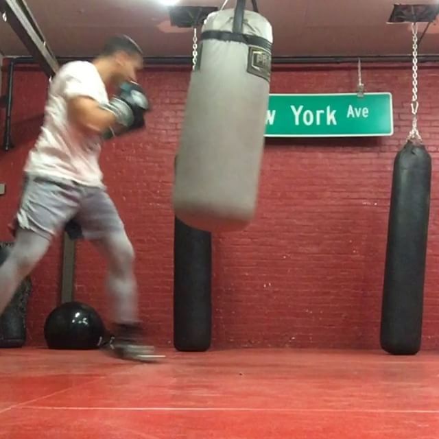 A man is boxing in front of a sign that says new york ave