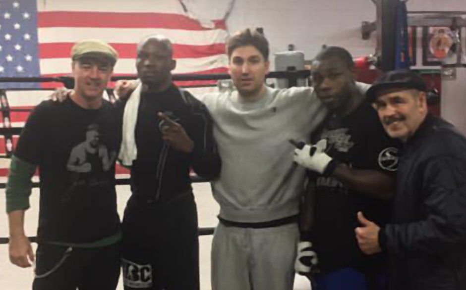 A group of men are posing for a picture in front of an american flag