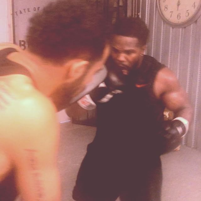 Two men are boxing in front of a clock that says 7:45