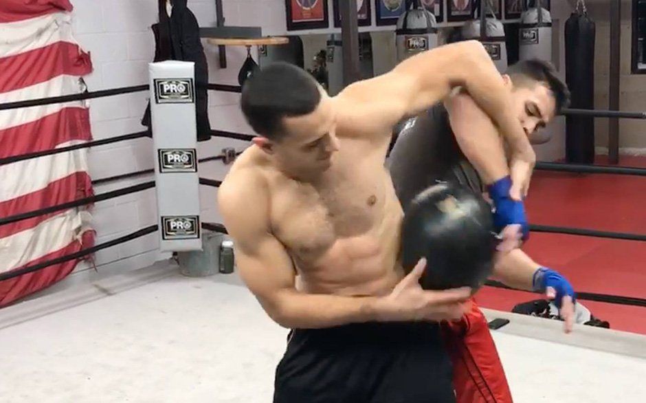 Two men are fighting in a boxing ring and one of them is holding a boxing glove.