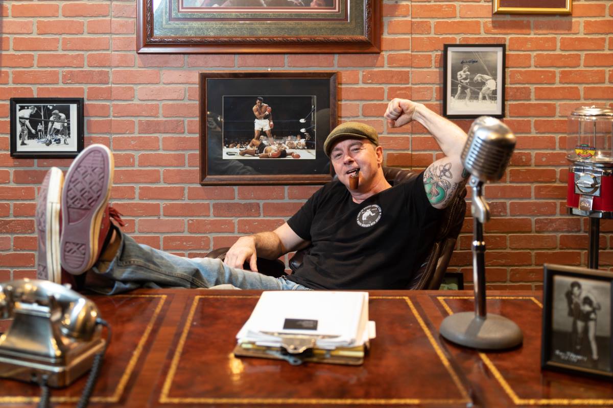 A man is sitting at a desk with his feet up in front of a microphone