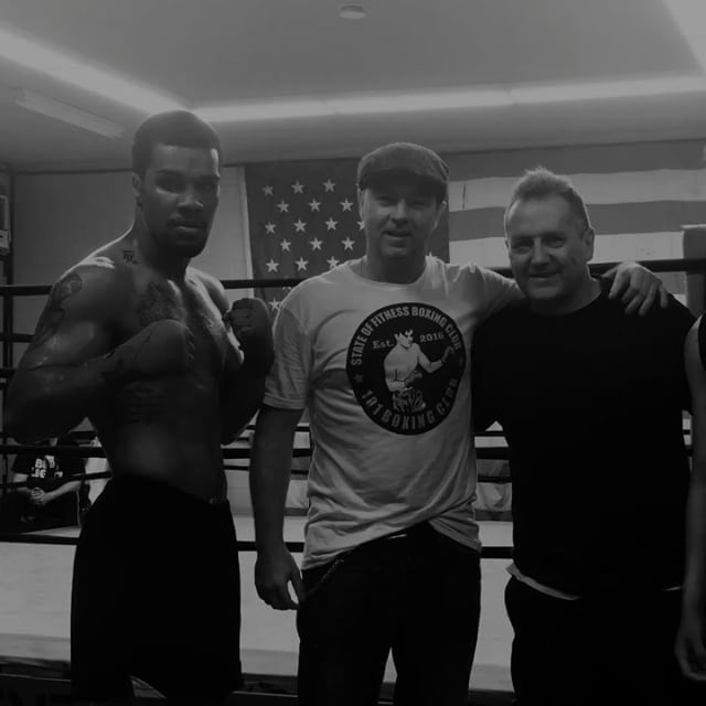 Three men posing for a picture in a boxing ring