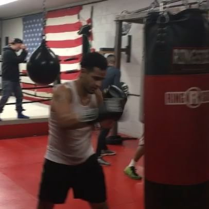 A man in a white tank top is boxing in a gym