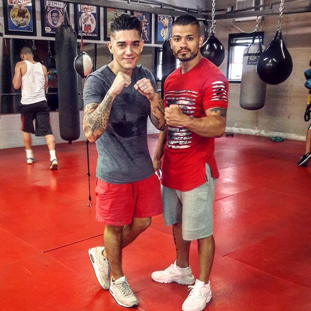 Two men are posing for a picture in a boxing gym