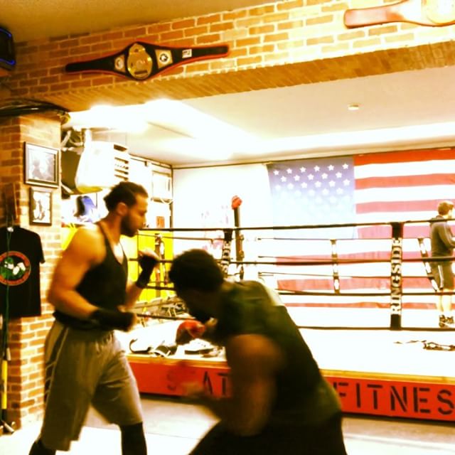Two men are boxing in a gym with a sign that says fitness