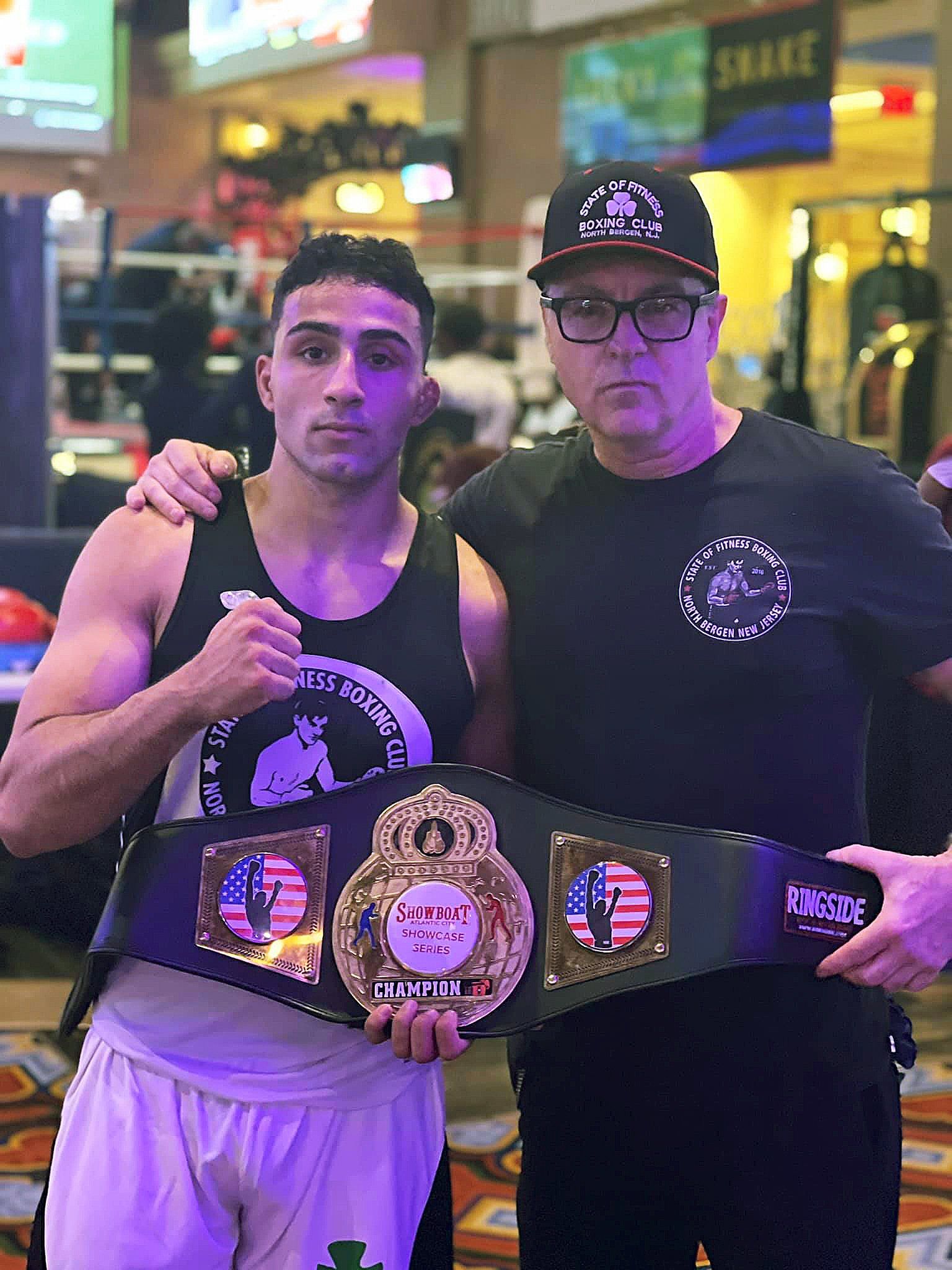 A man and a boy are posing for a picture while holding a boxing belt.