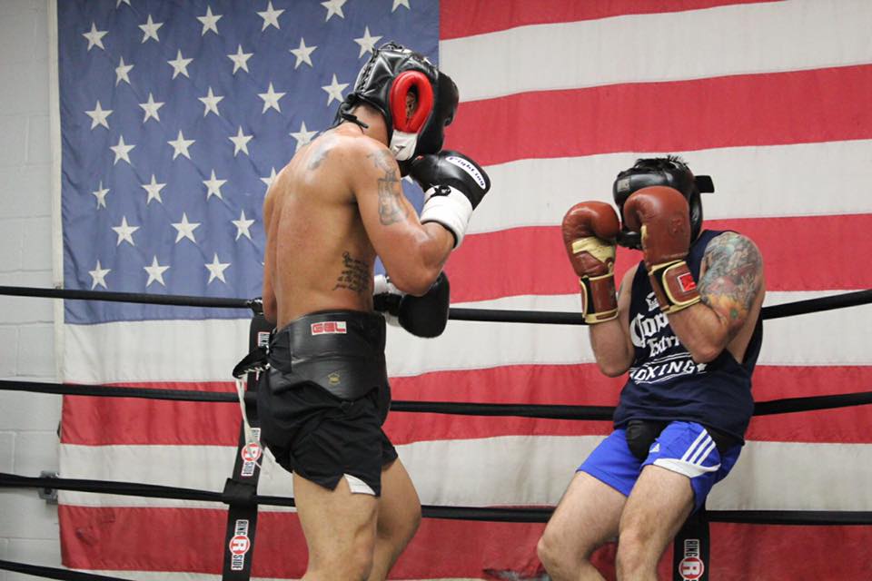 Two men are boxing in front of an american flag