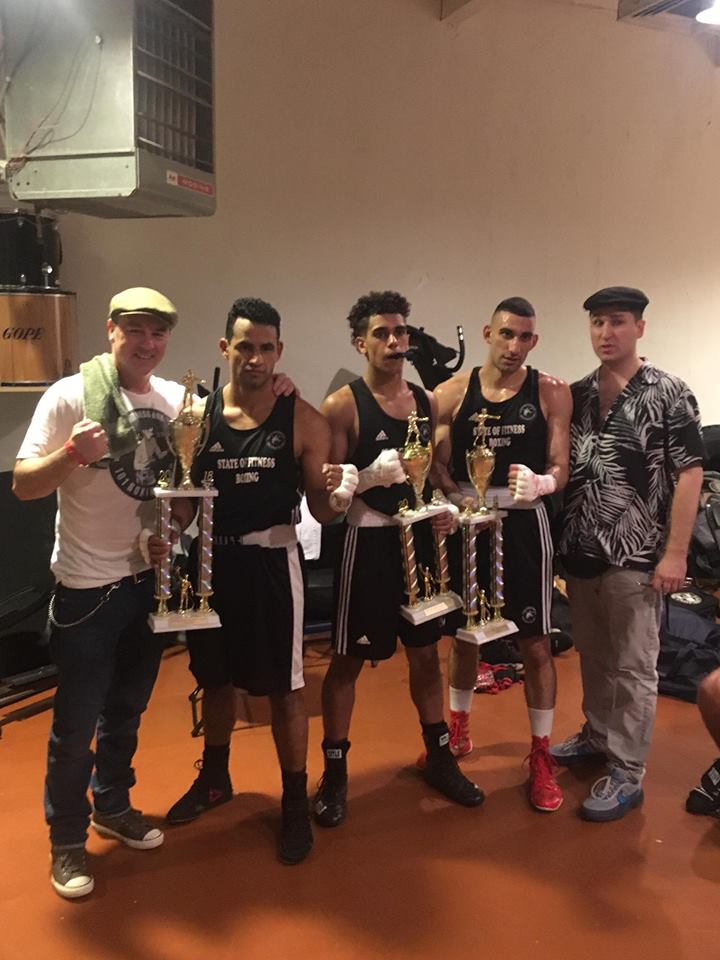 A group of men are standing next to each other holding trophies.