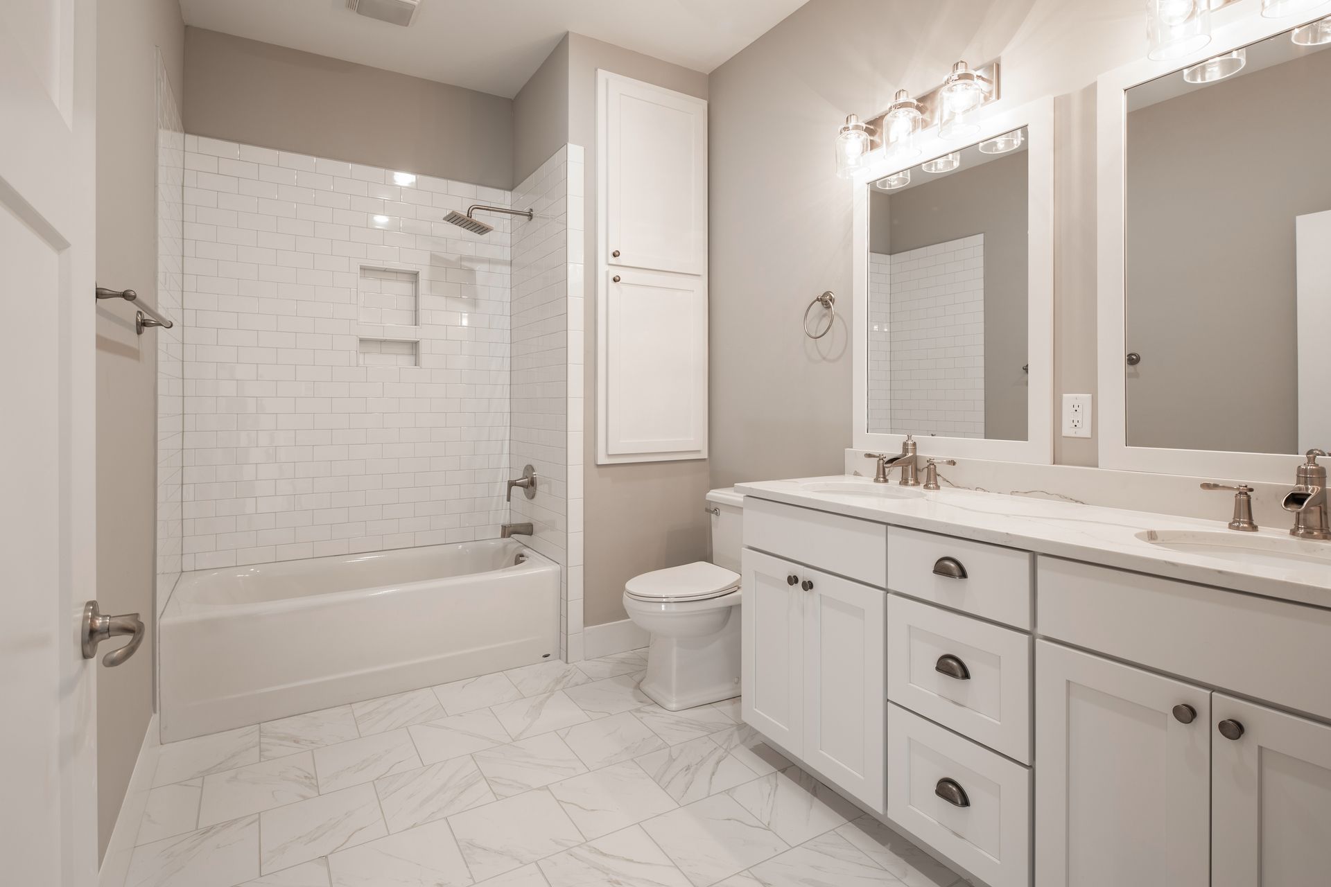 Bright white bathroom with double vanity, large mirror, and tiled tub-shower combo.