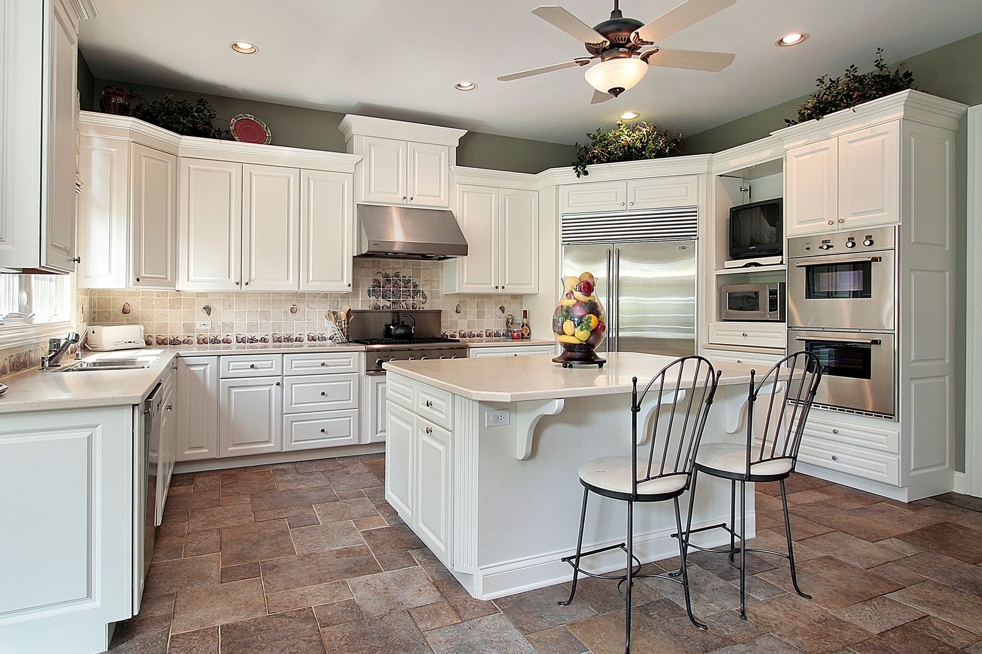 Bright white kitchen with island, stainless steel appliances, and two barstools