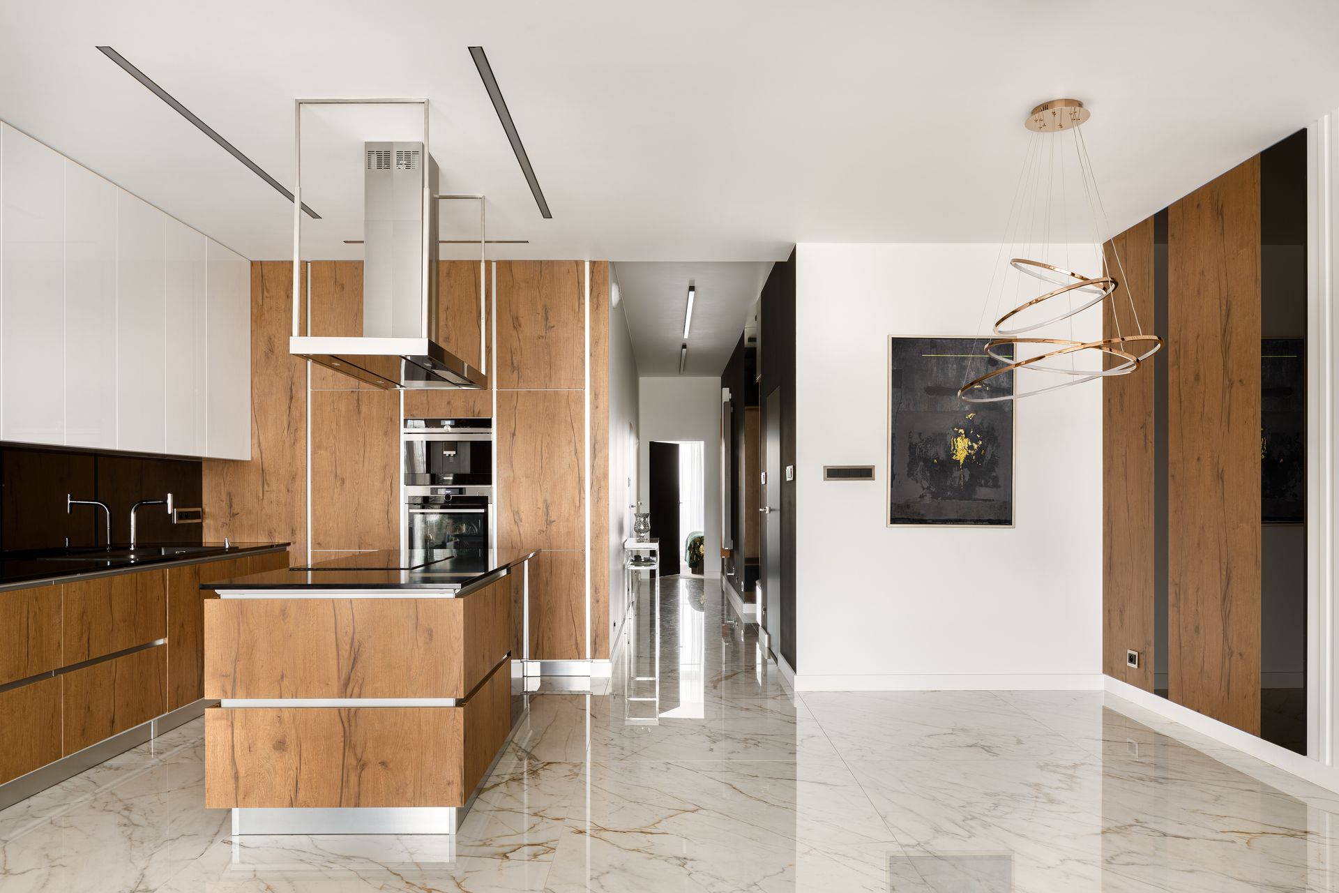 Modern minimalist kitchen with wood cabinetry, white walls, glossy marble floor, and island in a bright open interior