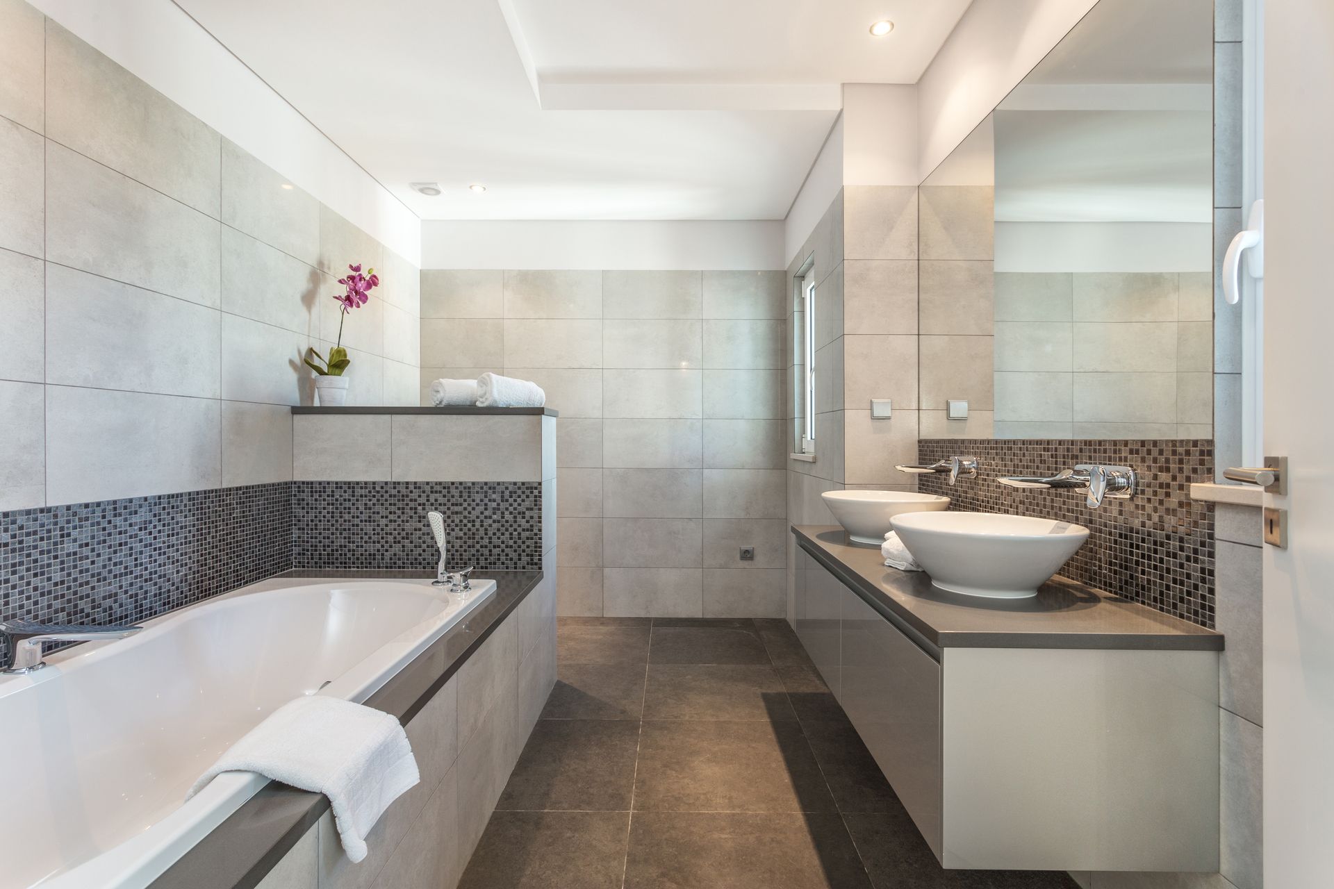 Modern bathroom with a bathtub, walk-in shower, and double sink vanity in gray tile tones