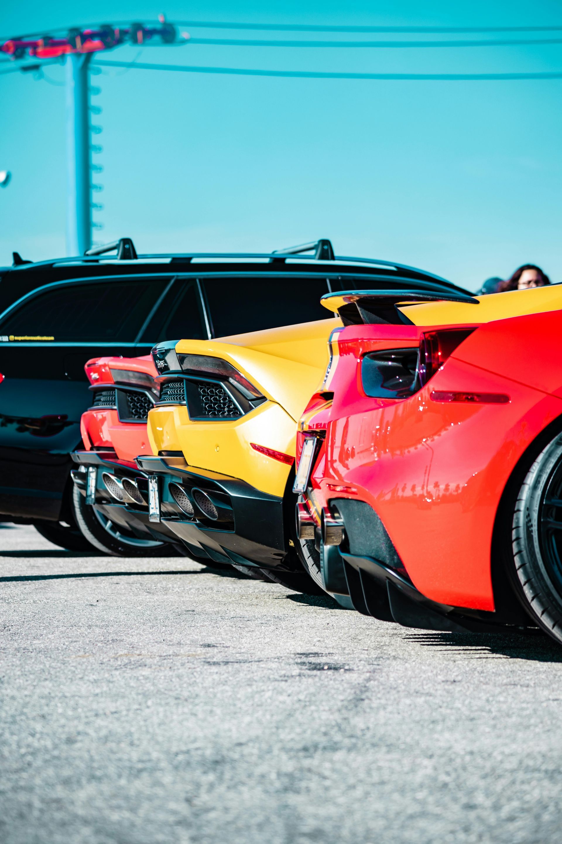 Une rangée de voitures de sport colorées garées sur l'asphalte par une journée ensoleillée.