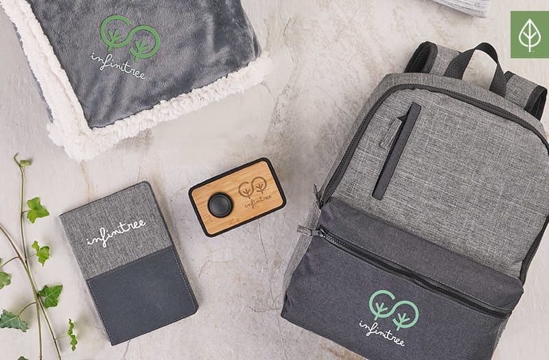 A backpack , a blanket , a notebook , and a speaker are sitting on a table.