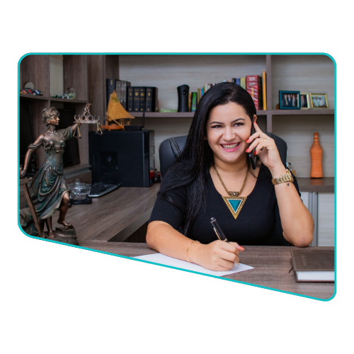 Female attorney in office smiling, talking on phone, writing on paper, statue with scales of justice visible.