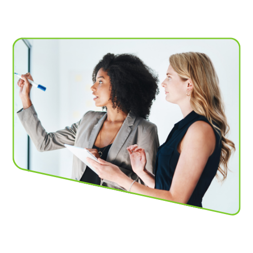 Two women in business attire collaborating at a whiteboard.
