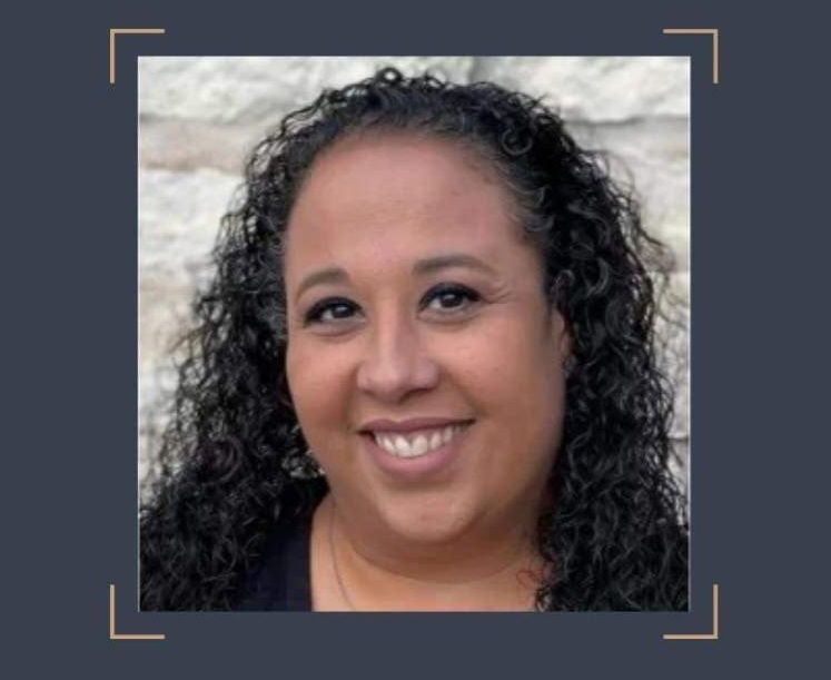 A woman with curly hair is smiling for the camera.