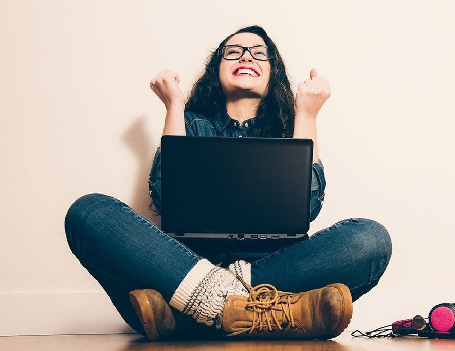 A woman is sitting on the floor using a laptop computer.