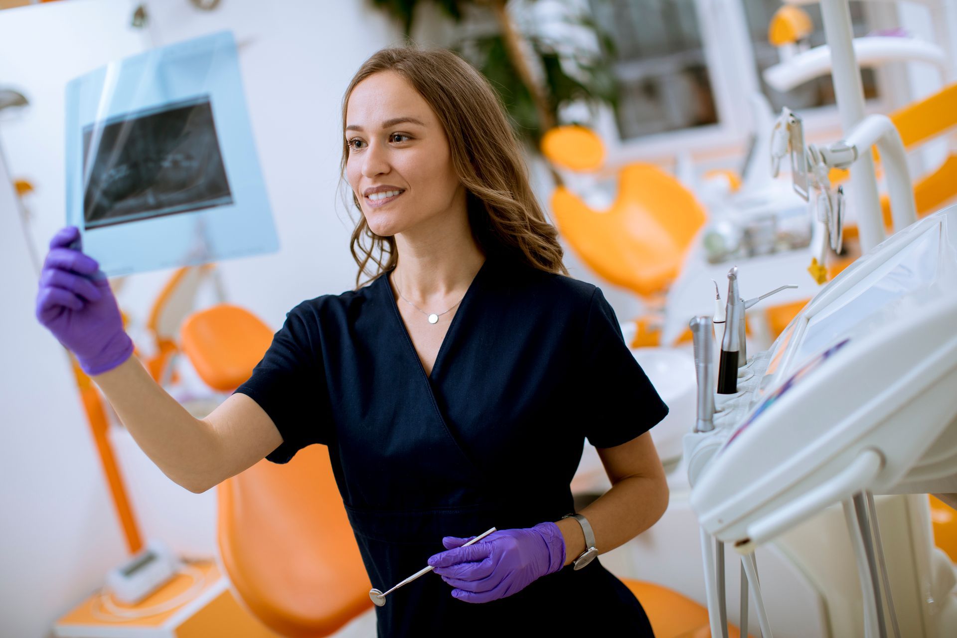 A female dentist is looking at an x-ray in a dental office.